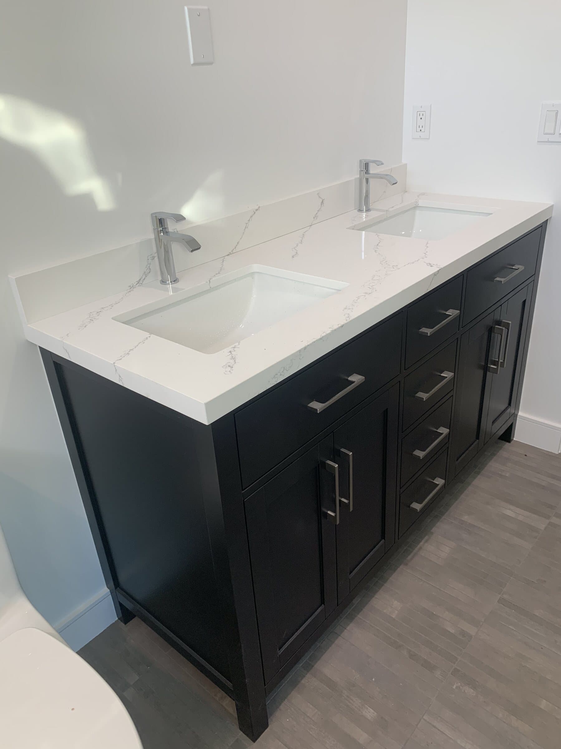 Double vanity with dark shaker cabinets, a white quartz top and two undermount sinks with chrome faucets in a newly finished bathroom
