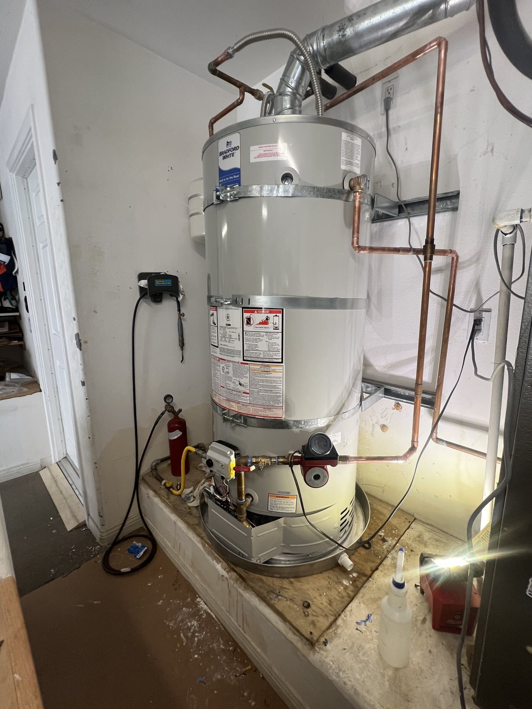 Tank water heater in an interior closet with copper supply lines, a thermal expansion tank, seismic strapping and a drain pan