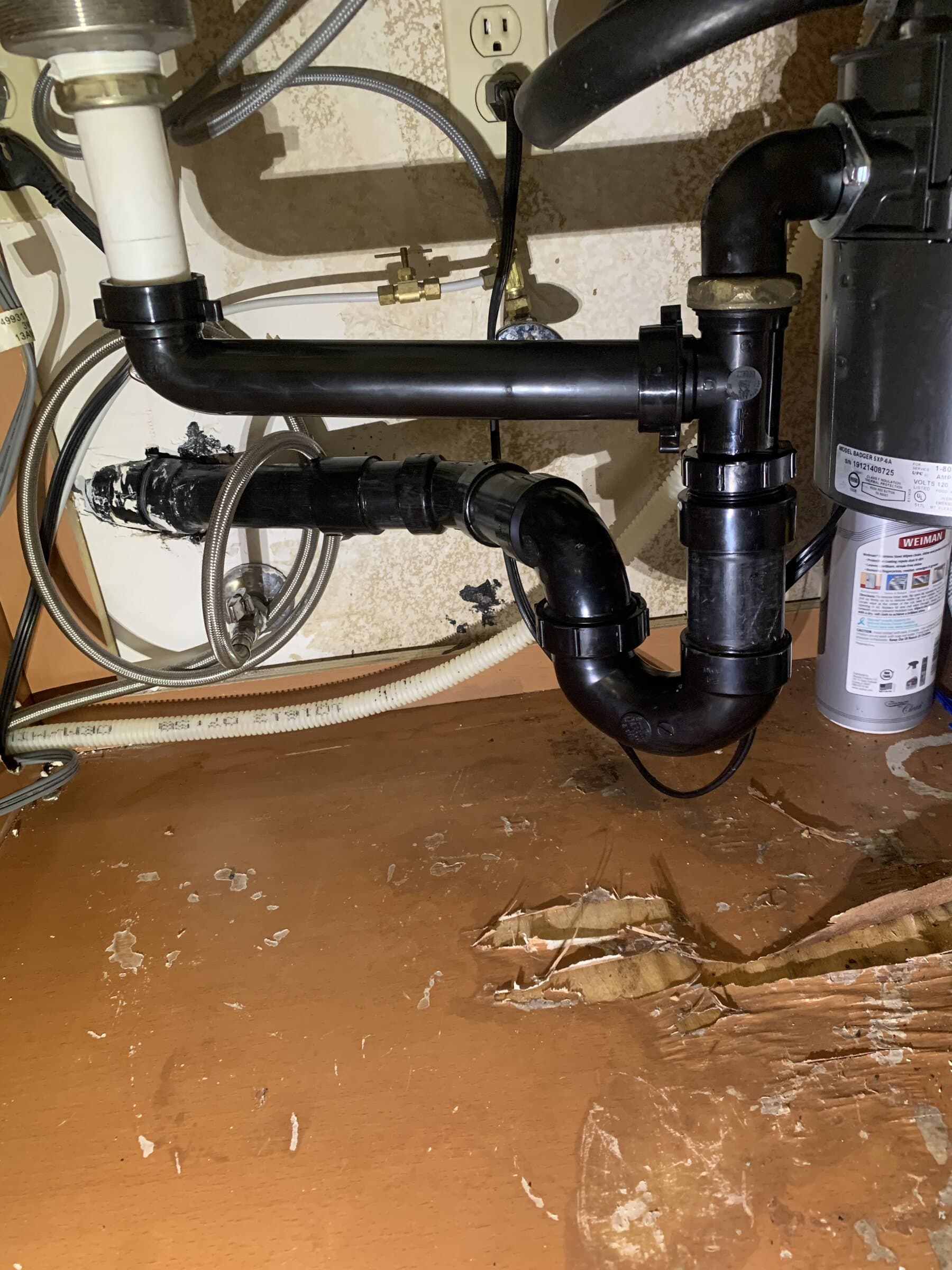 Under-sink ABS waste piping with a P-trap, waste arm and garbage disposal connection in a kitchen cabinet